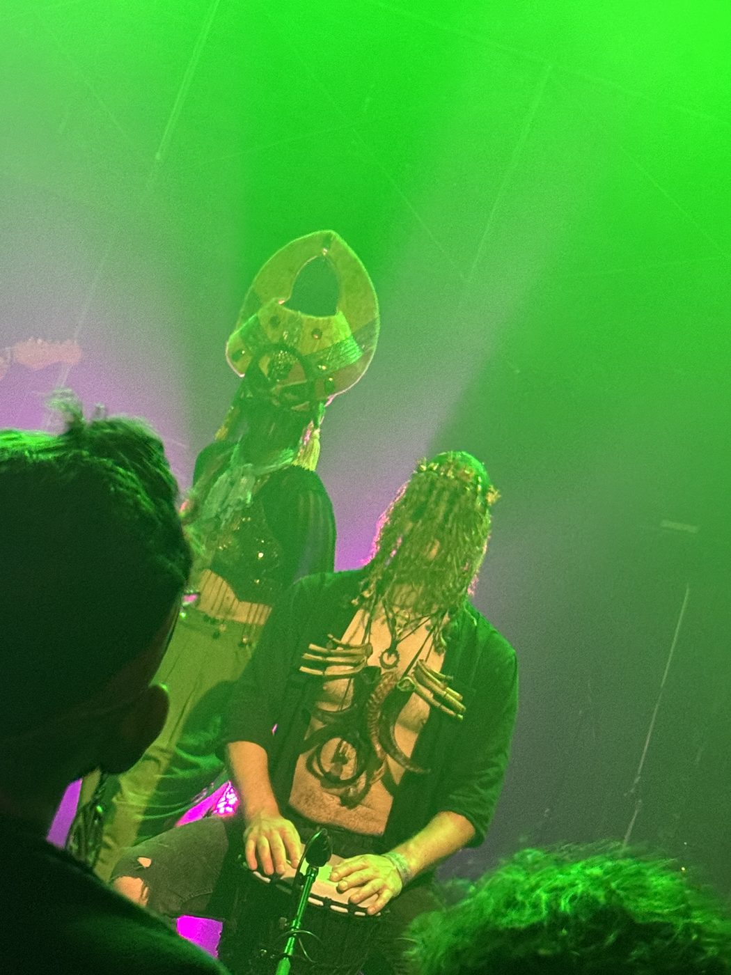 Bone Shirt Guy playing djembe under green light at The Concert Hall, Toronto