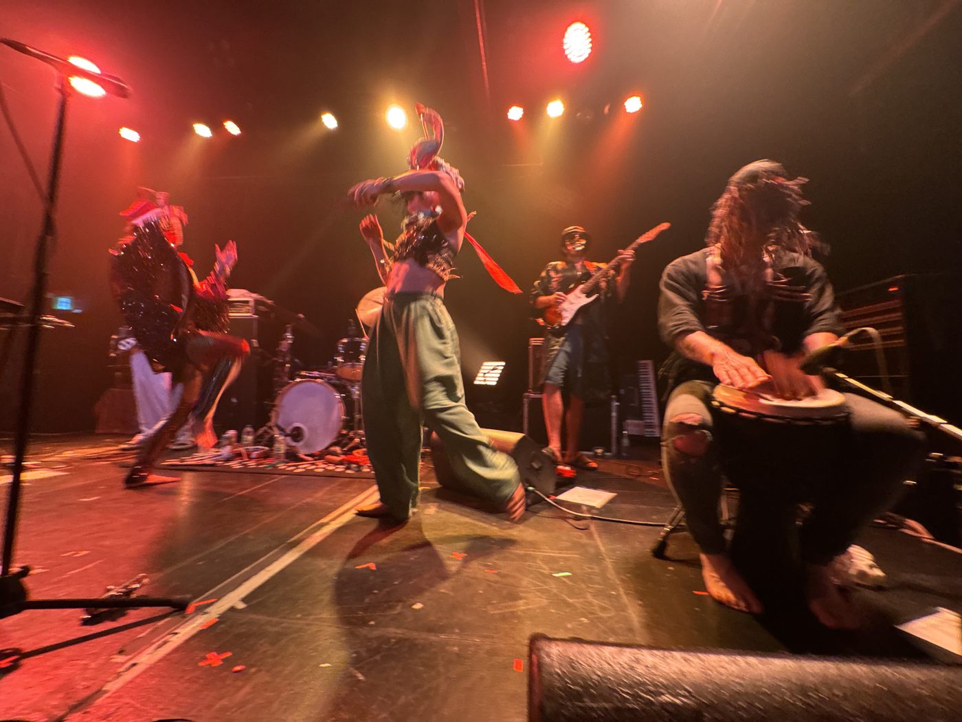 Full band in motion on stage at Bridgeworks — singers, guitarist, and djembe player